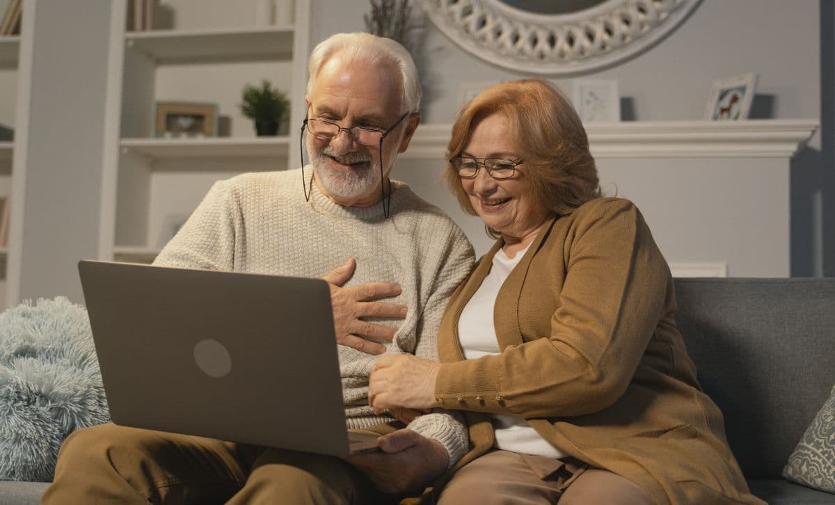 An older couple reviewing their retirement accounts on a laptop at home