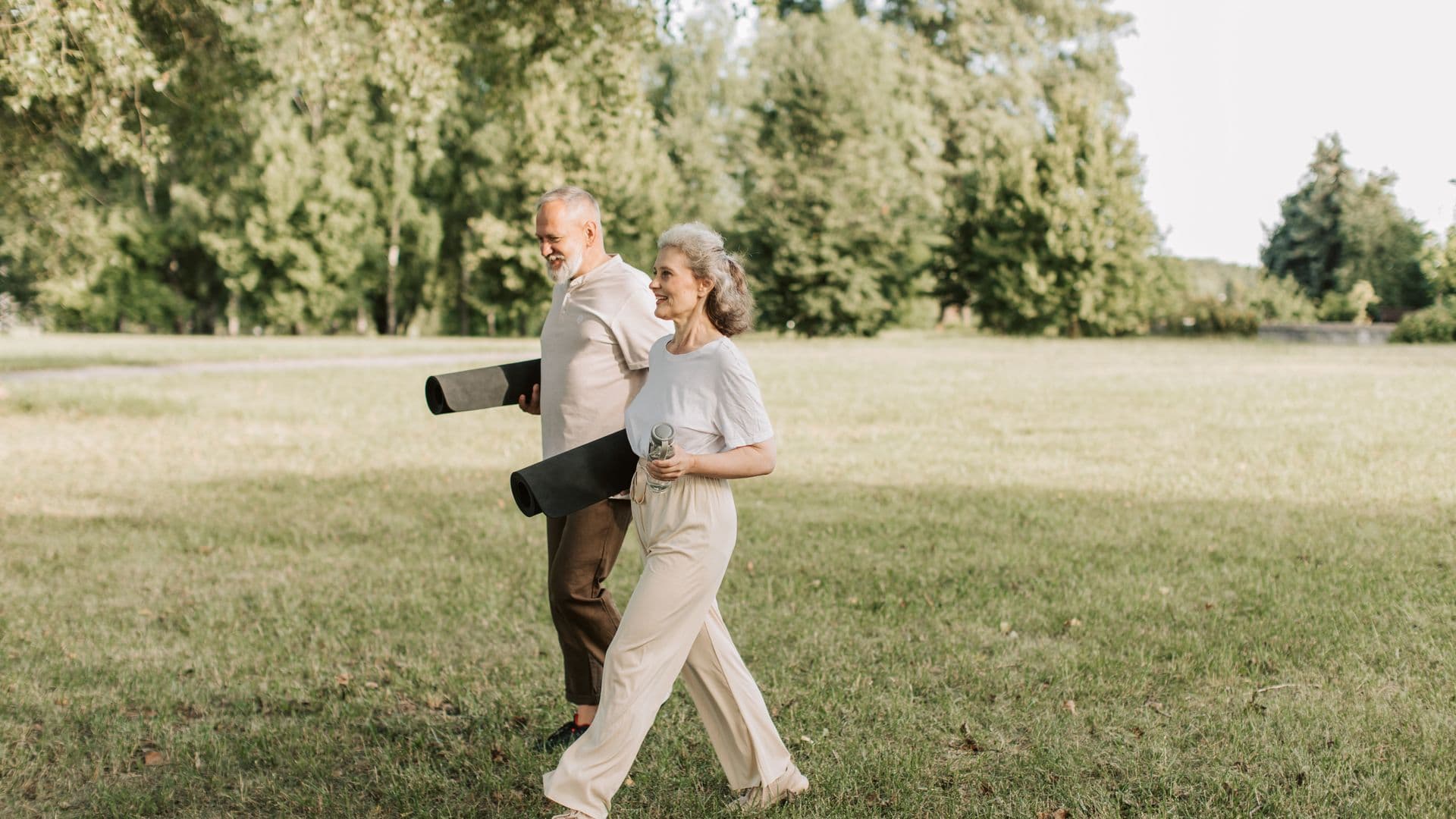 An older couple walking together through a park on a bright morning